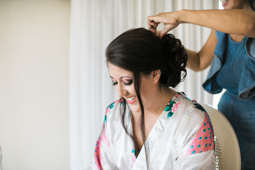 Bride laughs as she gets her hair done before her wedding