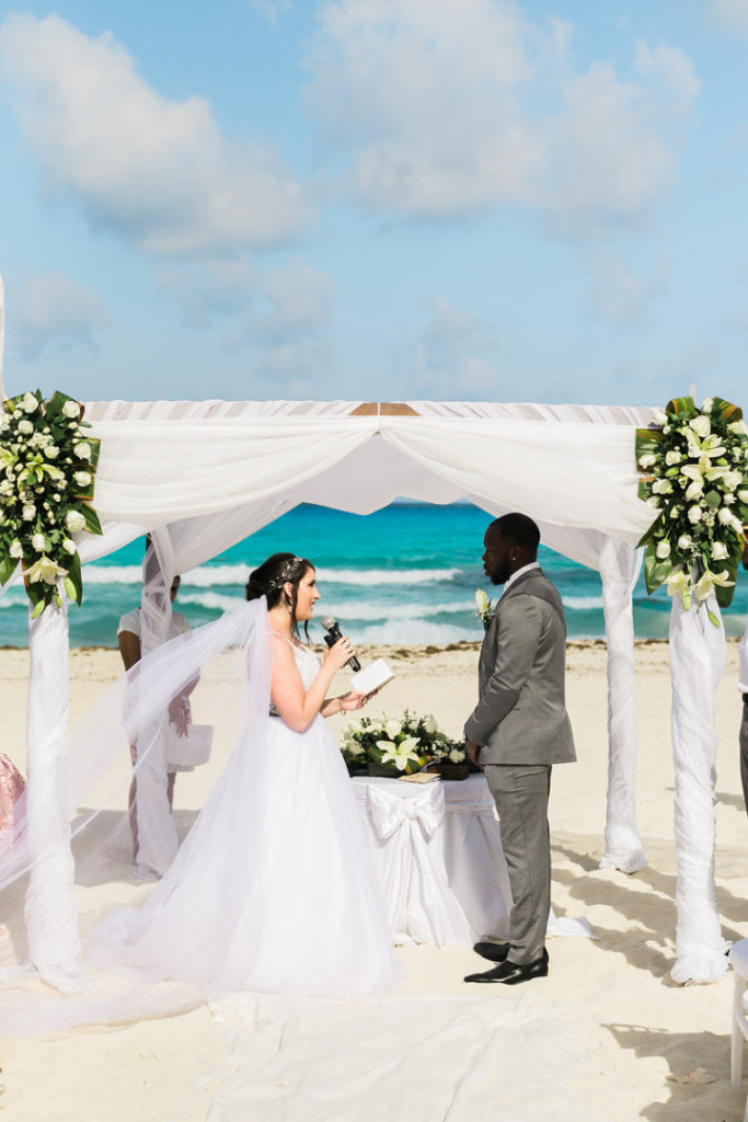 bride and groom exchange vows on the beach of the Crown Paradise Club in Cancun, Mexico
