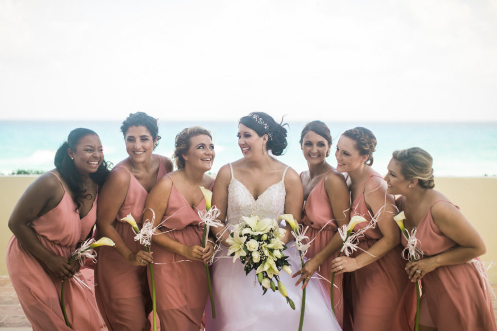 Bride and bridesmaids pose on the beach of the Crown Paradise Club