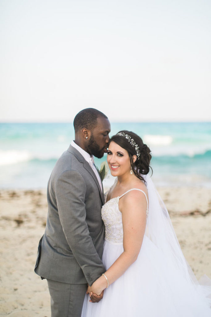 Bride and groom pose on the beach of the Crown Paradise Club in Cancun, Mexico