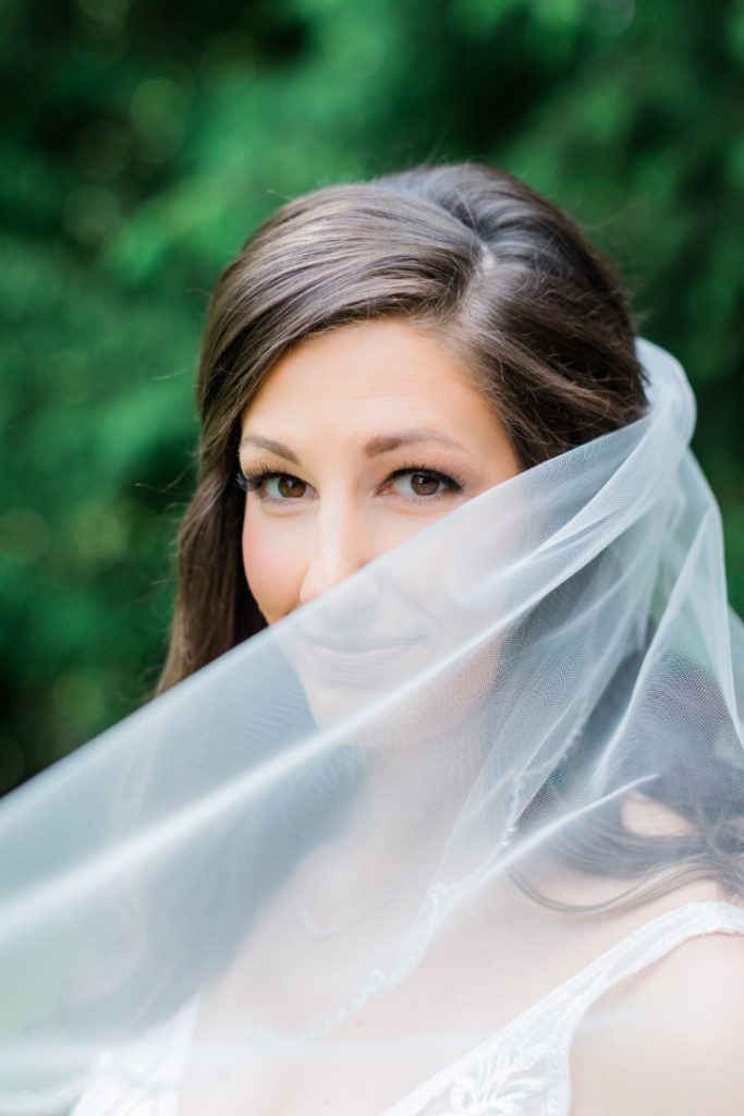Bridal portrait of bride smiling with her veil blowing across her face