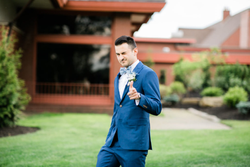 Groom points and winks at the camera as he walks to his summer Edgewood Club Wedding