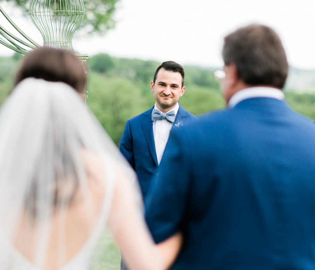 Groom smiles as bride approaches him