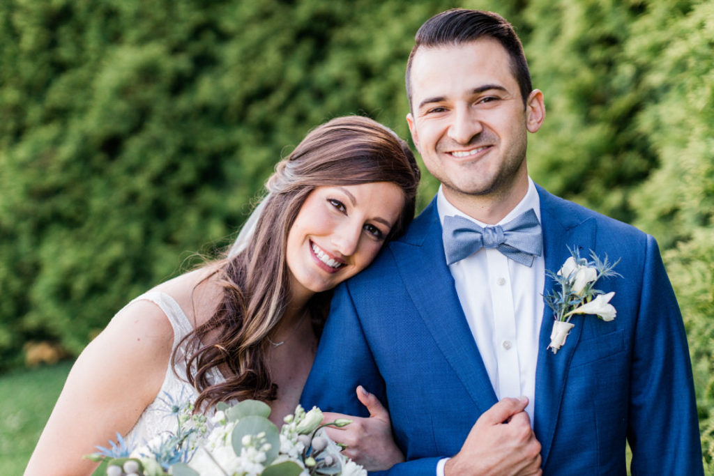 Bride and groom smile at the camera after their summer Edgewood Club wedding ceremony