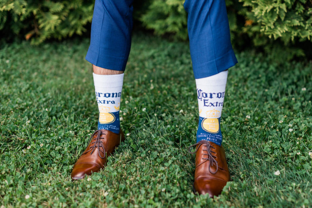 Groom's legs, with pants pulled up showing Corona Extra socks with shoes