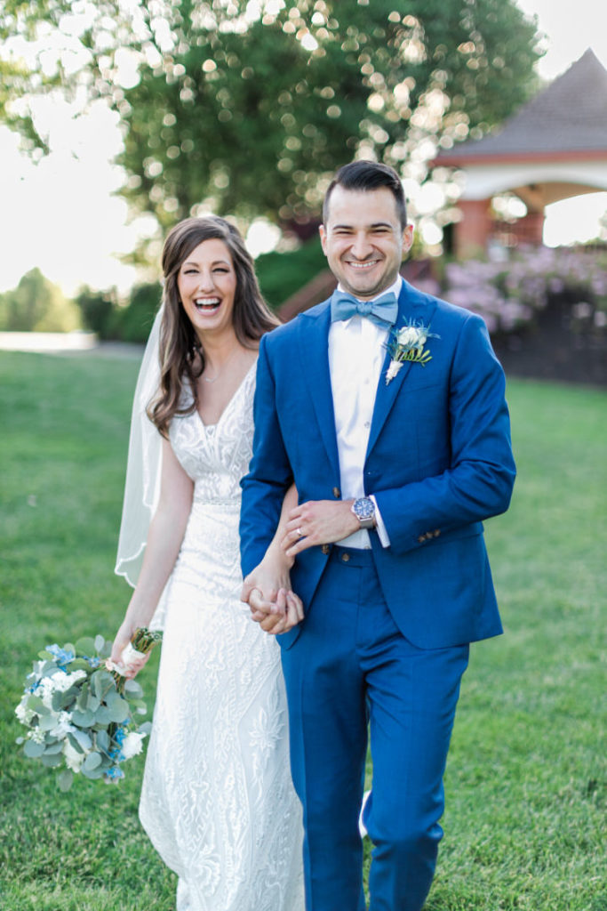 Bride and groom hold hands and walk together while laughing