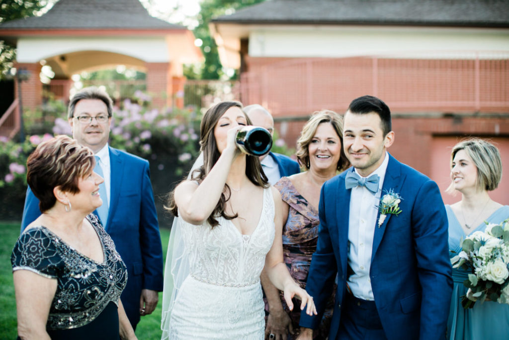 Bride drinks from bottle of champagne