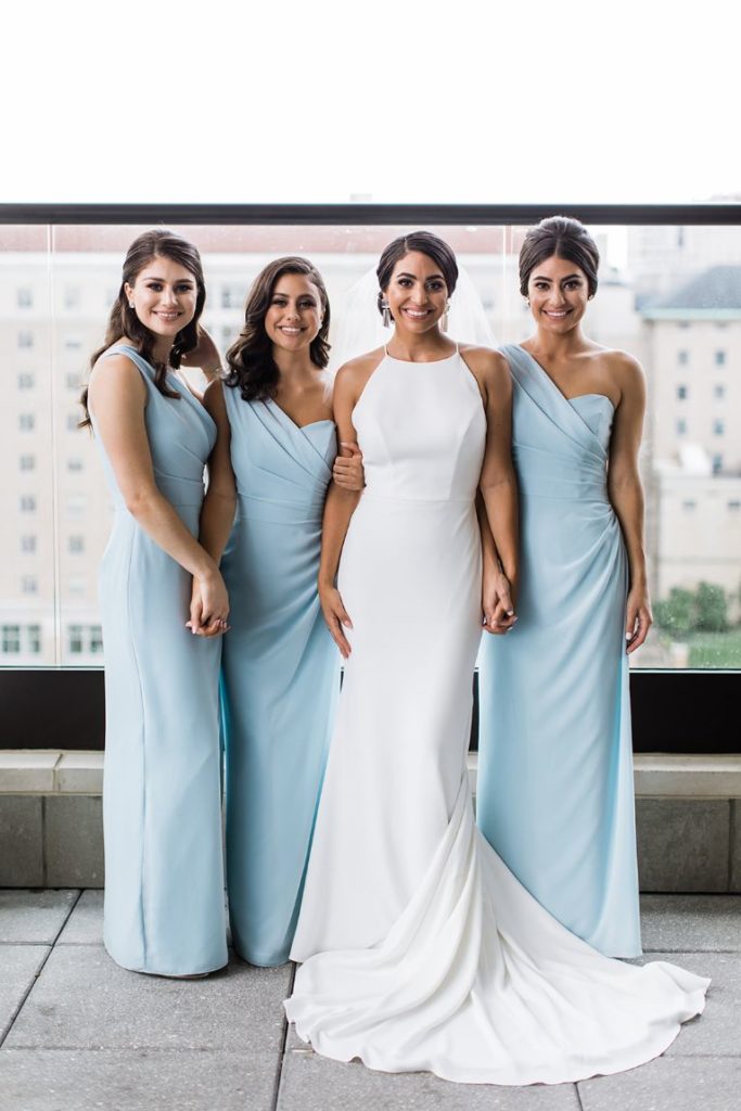 Bride and her sisters pose together in bridesmaid dresses and wedding gown