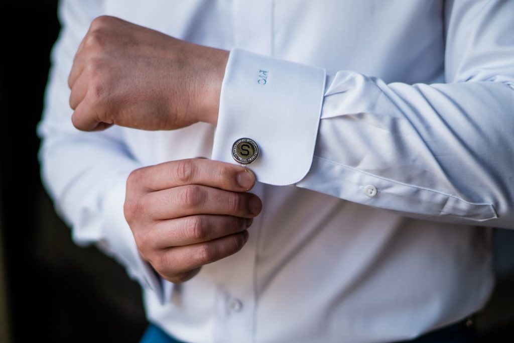Close up photo of groom buttoning his cuff links