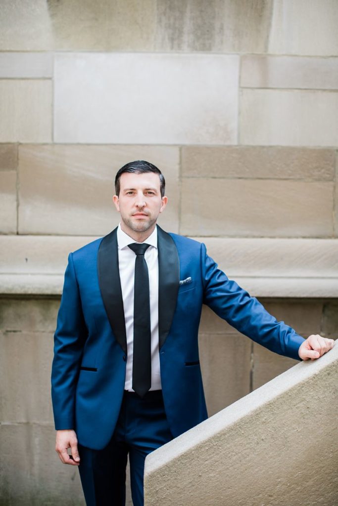 Groom poses in navy blue and black suit