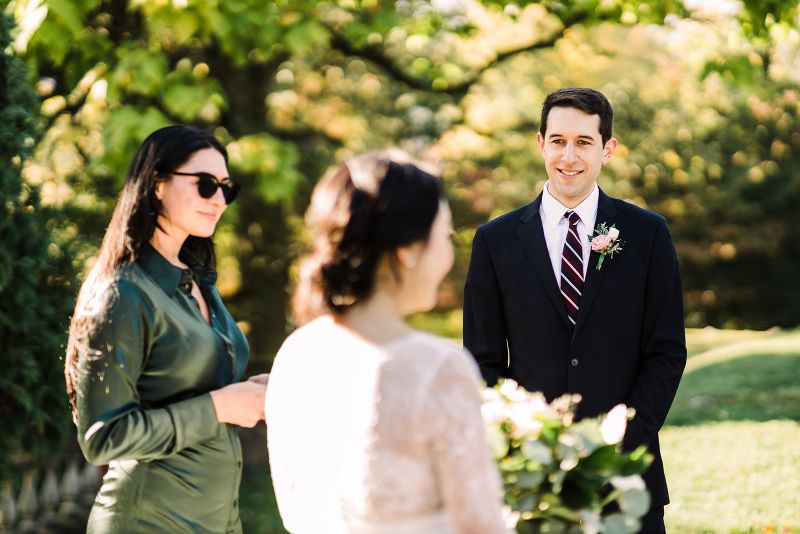Groom smiles at the bride as the wedding officiant looks on