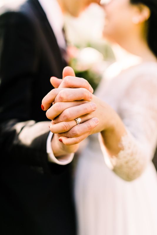 Macro photo of bride and grooms hands and rings