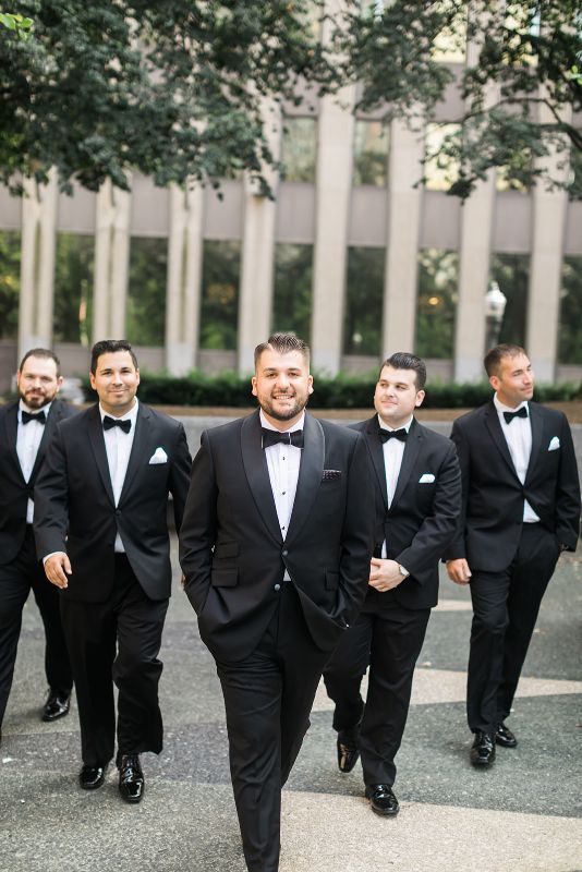 Groom walks with groomsmen in Mellon Square