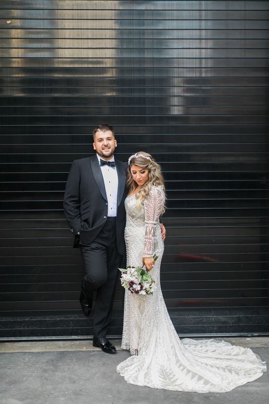 Bride and groom pose against black wall in downtown Pittsburgh