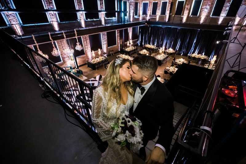 Bride and Groom Kiss in balcony above Glam Pittsburgh Opera Wedding reception