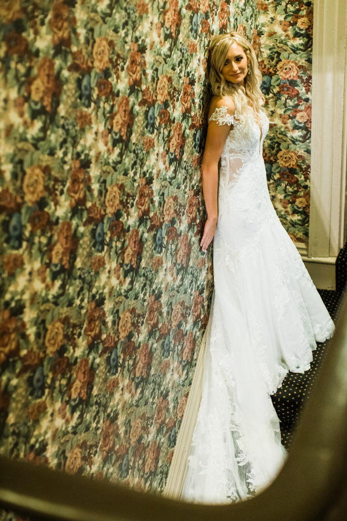 Bride poses against a wall with floral wallpaper in the Morning Glory Inn