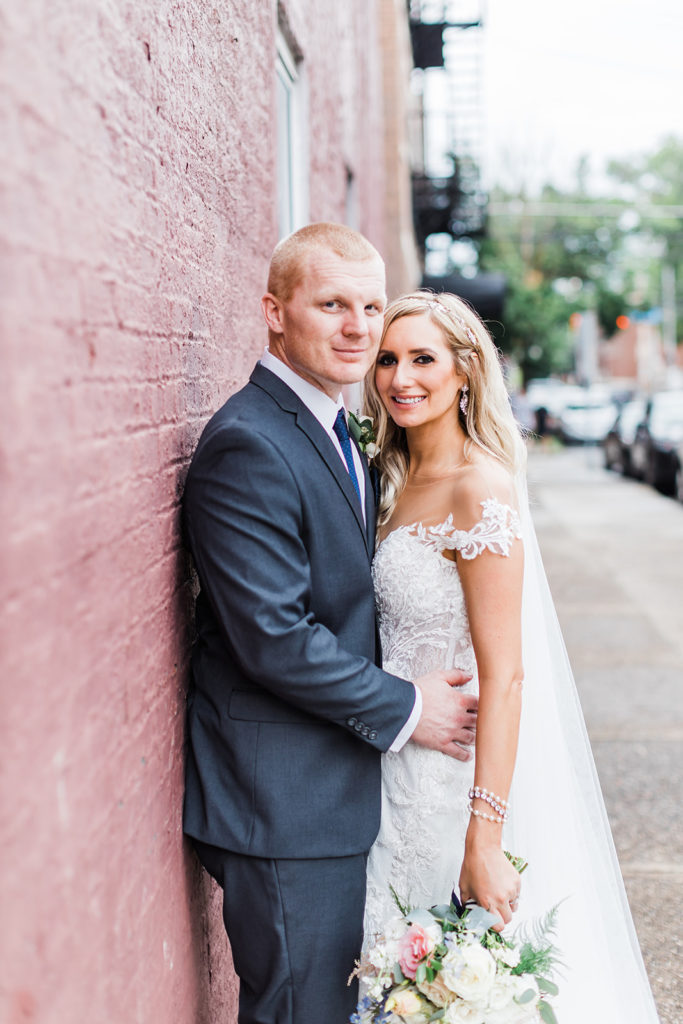 Bride and groom portrait against pink brick wall