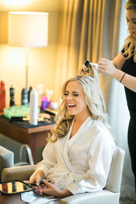 Bride laughs as her hair is done by hairdresser