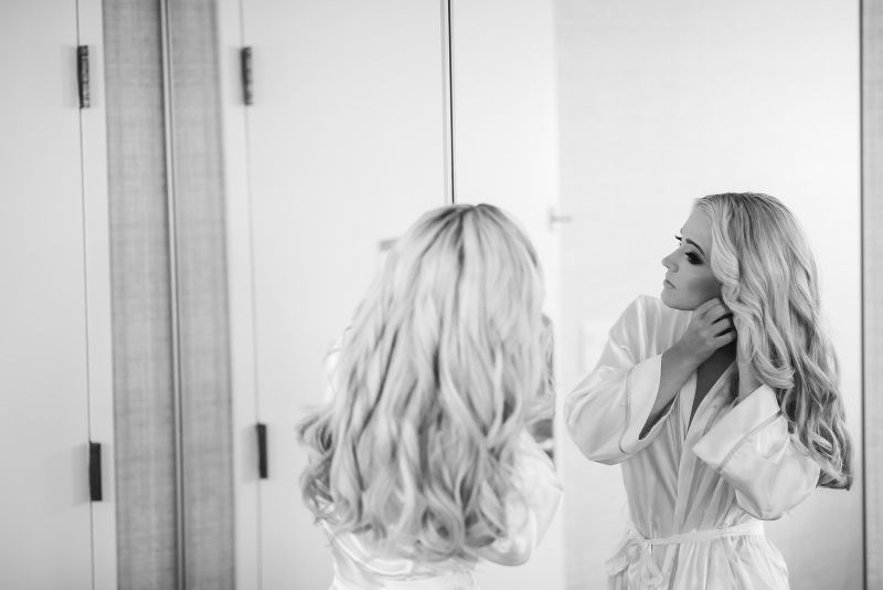 Bride puts on earrings in the mirror