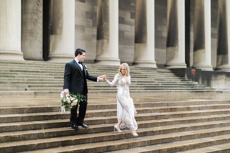 Bride and Groom walk together at the Carnegie Mellon College of Engineering pillars
