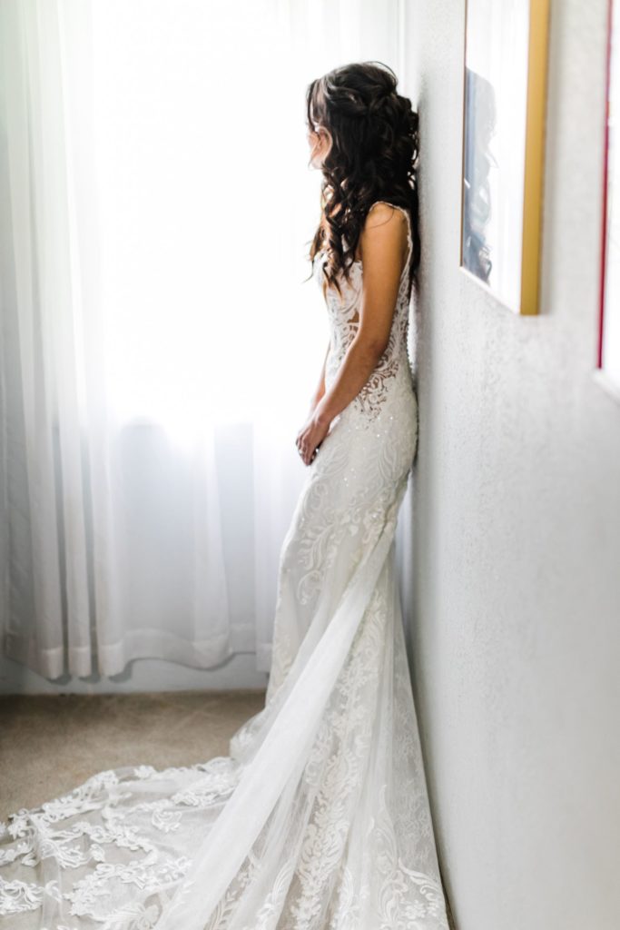 Bride in a wedding dress standing against a wall