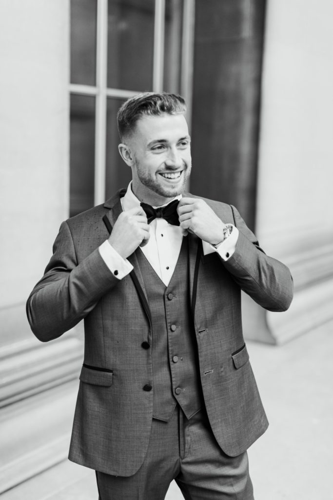 Groom smiles and adjusts his bowtie