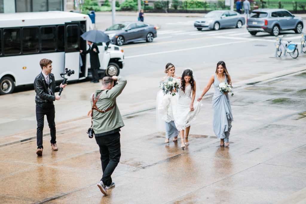 Action photo of Steven Dray Photography as he takes a photo of bride walking with bridesmaids
