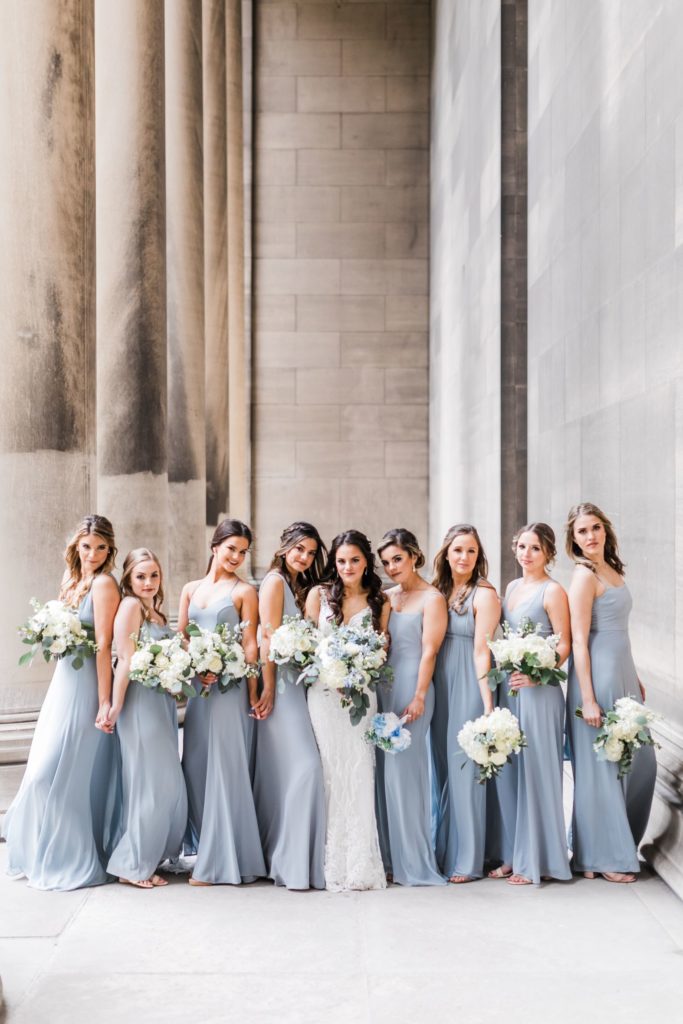 Bride poses with her bridesmaids wearing light blue bridesmaid dresses