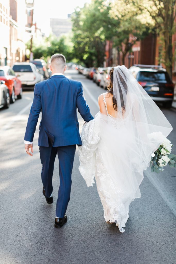 Bride and groom walk away from the camera, holding hands