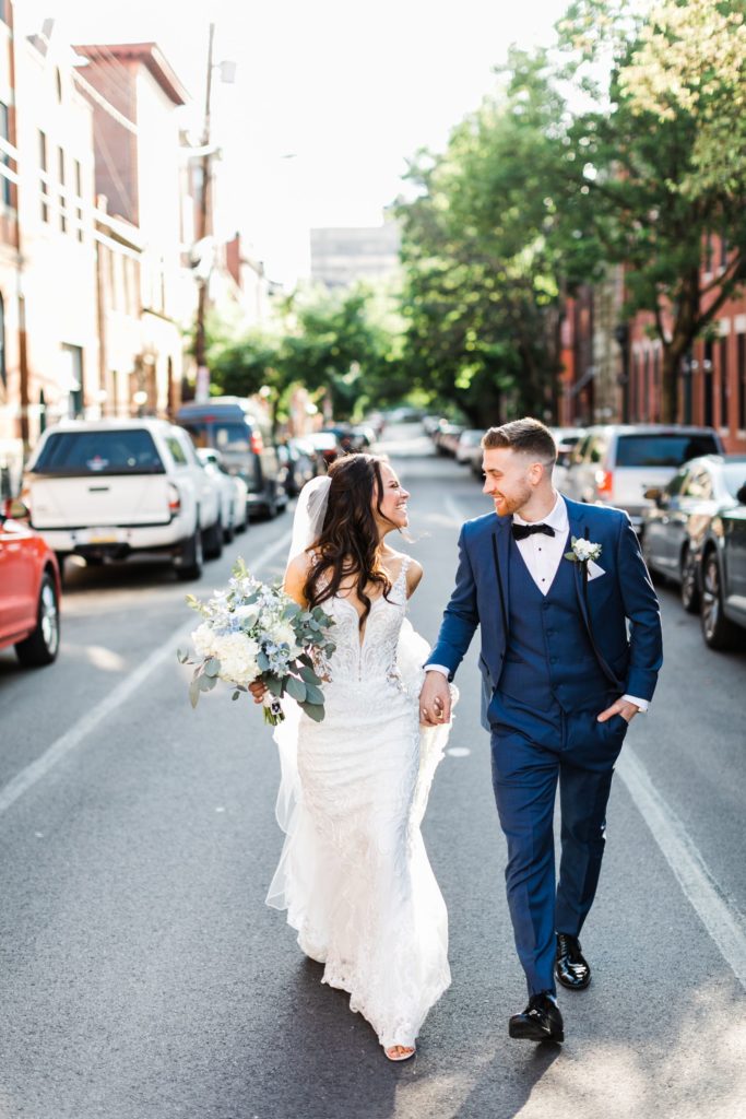 Bride and groom walk down the street together, looking at each other