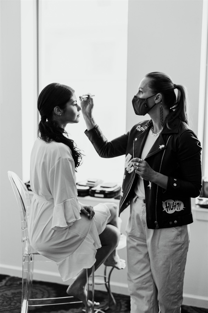 A makeup artist puts finishing touches on the bride