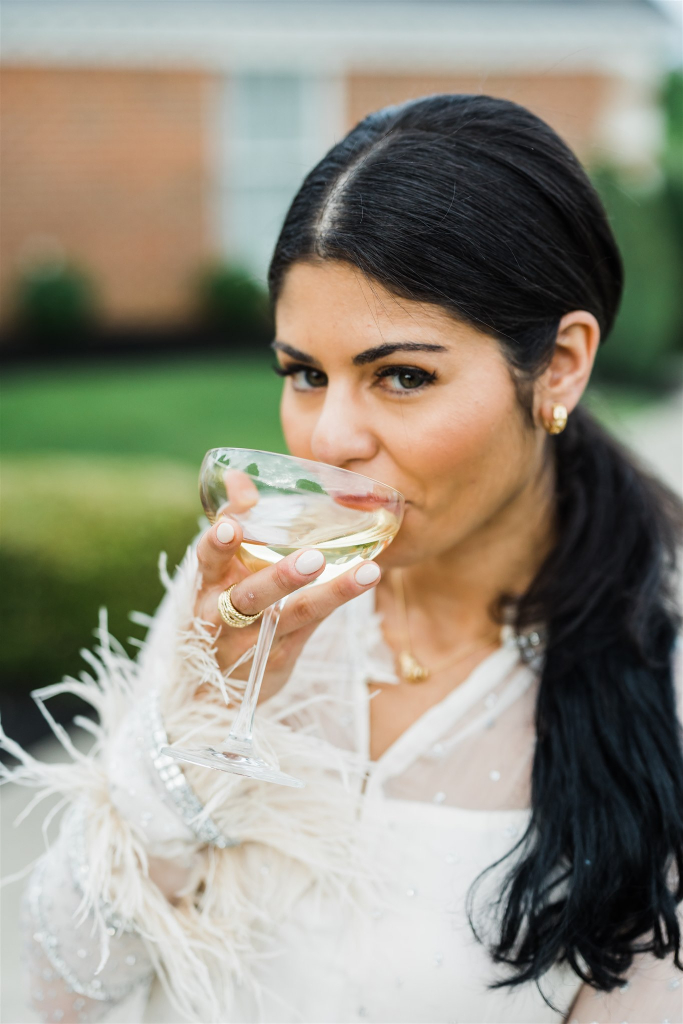 Bride poses in glam gown holding a champagne glass