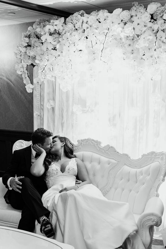 Bride and groom kiss in glamorous lounge area at monochromatic Nemacolin Resort wedding reception