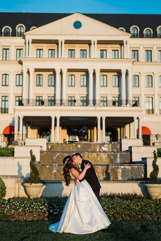 Bride and groom kissing in front of monochromatic Nemacolin Resort wedding 