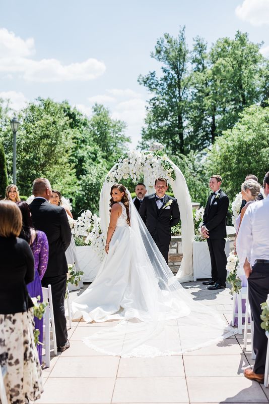Bride and groom smile and look over guests during their monochromatic Nemacolin Resort wedding ceremony