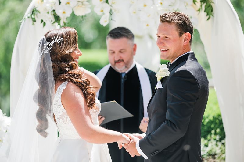 Bride and groom laugh as they say their vows at their monochromatic Nemacolin Resort wedding ceremony