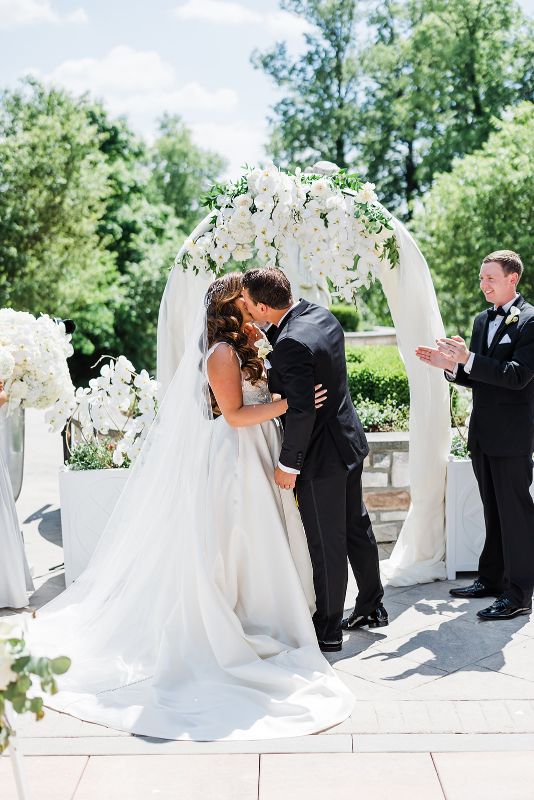 Bride and groom share first kiss at their monochromatic Nemacolin Wedding ceremony
