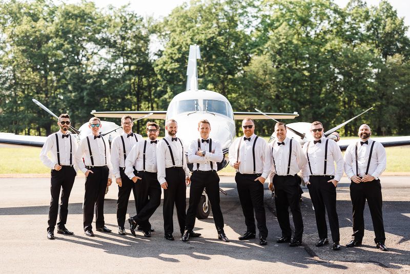 Groom and groomsmen pose in front of his plane