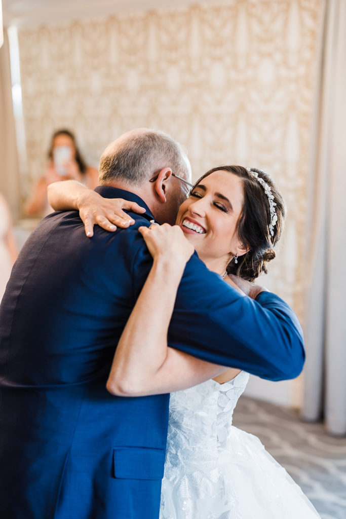 Bride smiles and hugs her father before she walks down the aisle