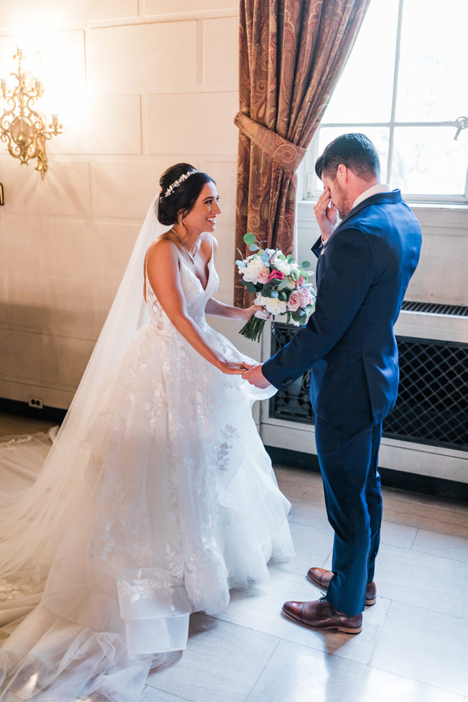 Groom cries as the bride smiles ecstatically as he sees her for the first time