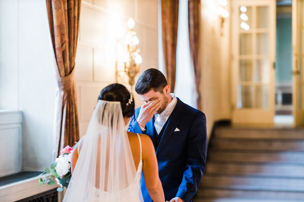 Groom cries as the bride smiles ecstatically as he sees her for the first time