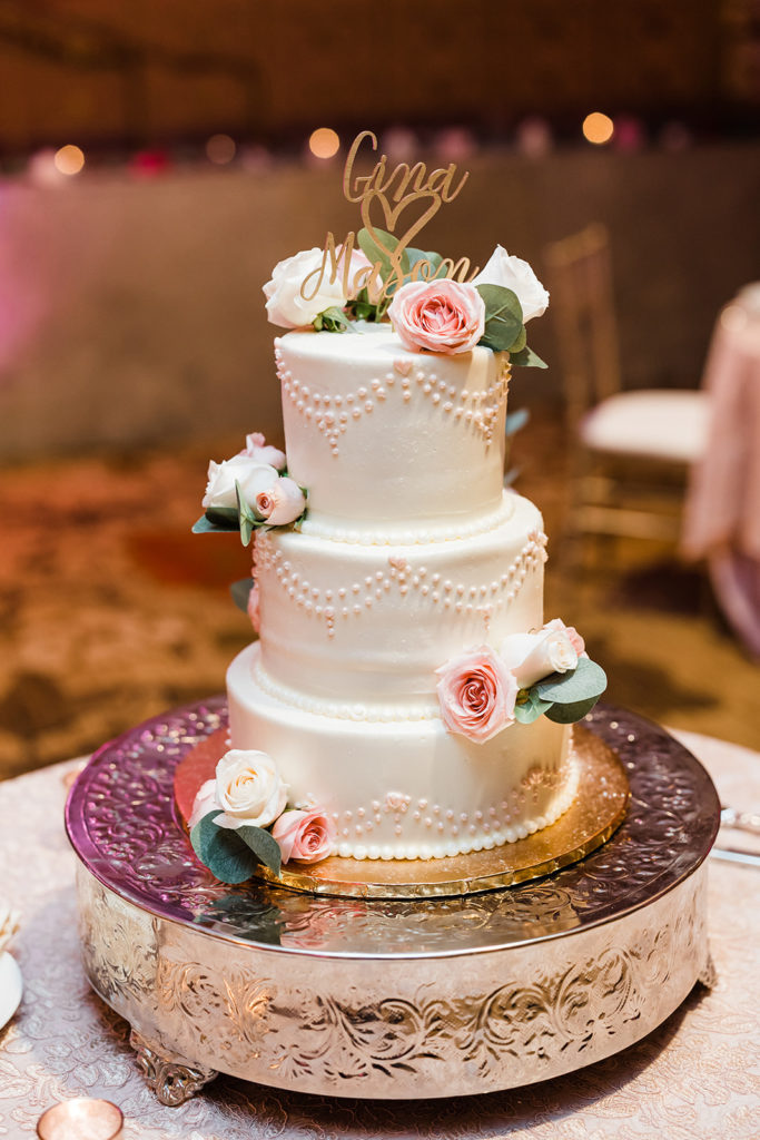 Three tiered wedding cake decorated with pearls and roses