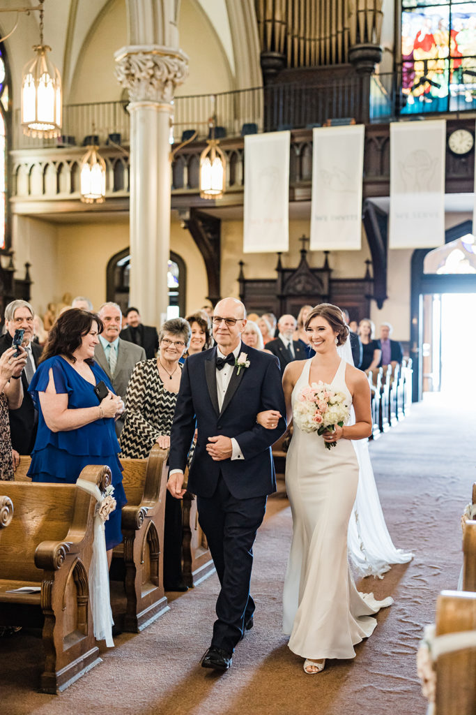 Bride and her gather walk down the aisle of St. Mary on the Mount church