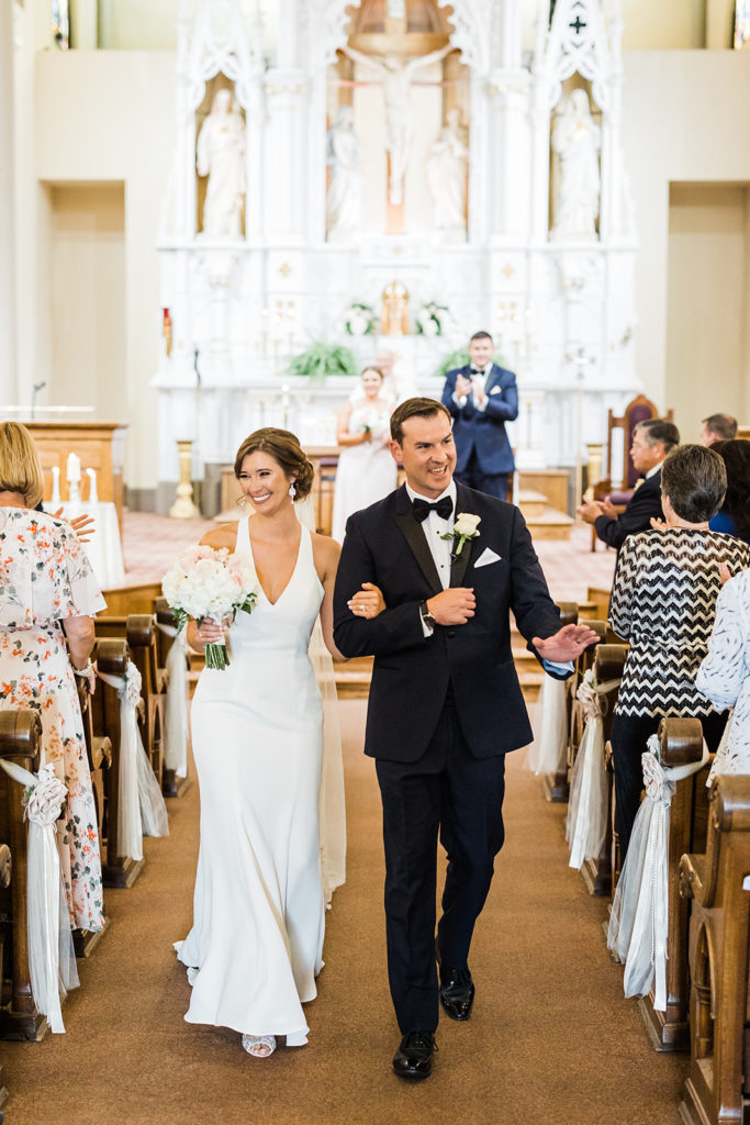 Bride and groom smile as they walk up the aisle of Saint Mary of the Mount church