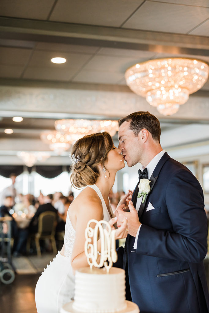Bride and groom kiss after cutting cake their Pittsburgh city view wedding reception