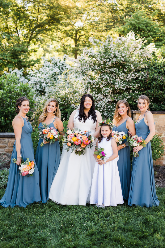 Bride poses with bridesmaids dressed in light blue Azazie bridesmaids dresses