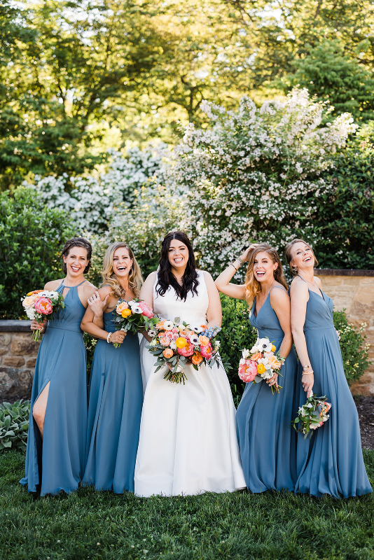 Bride poses with bridesmaids dressed in light blue Azazie bridesmaids dresses