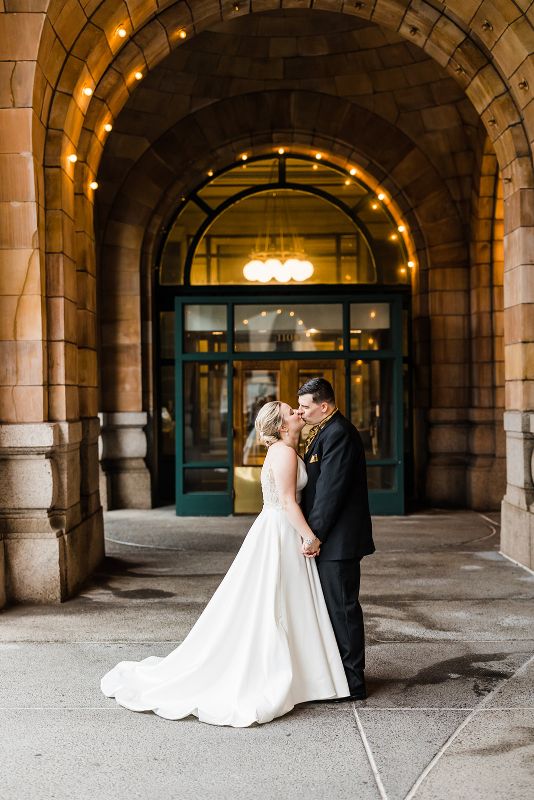 Bride and groom kiss in front of the Pennsylvanian at their downtown Pittsburgh vow renewal