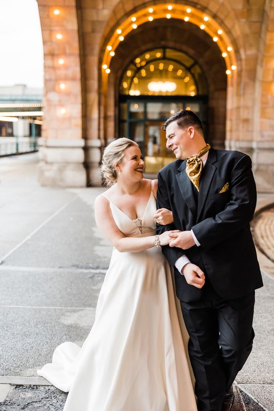 Bride and groom walk together in front of the Pennsylvanian at their downtown Pittsburgh vow renewal