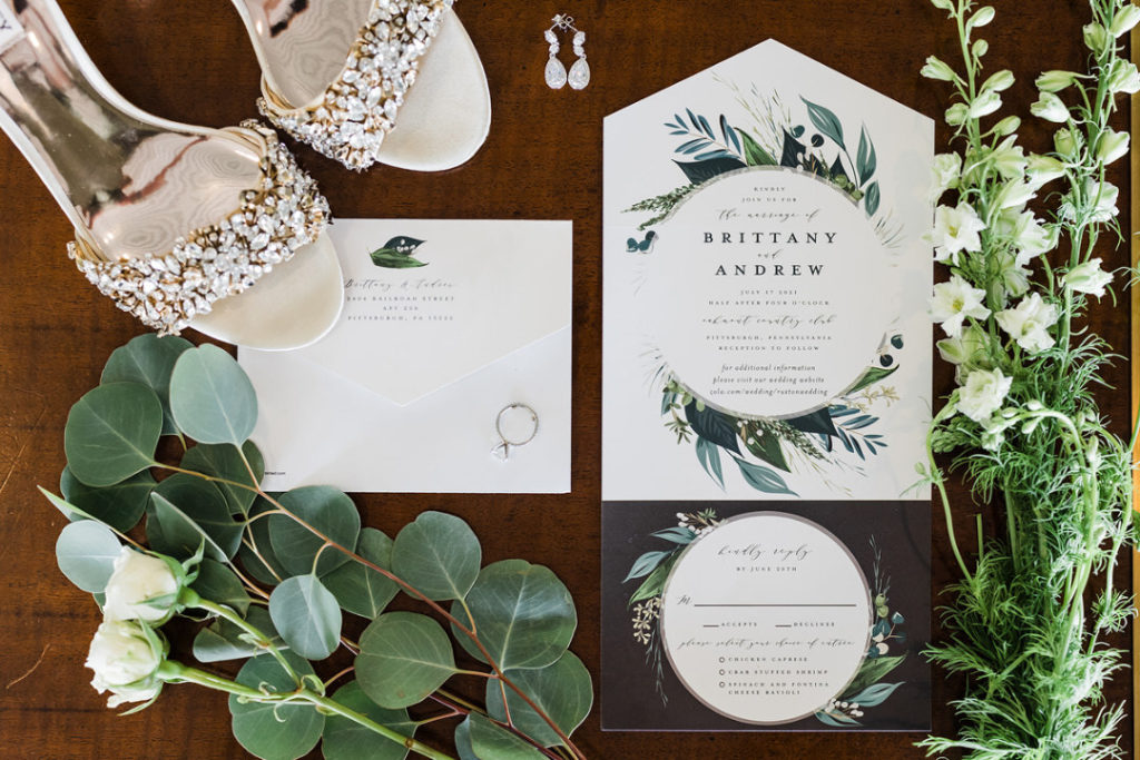 Wedding invitation suite flat lay with ivory and green florals